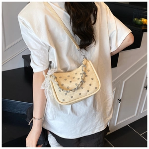Détail du sac clouté avec chaîne argentée et breloque perle en dentelle sur modèle