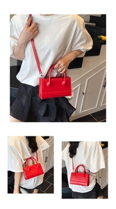 Close-up of red structured mini bag with spherical handle detail and crossbody strap