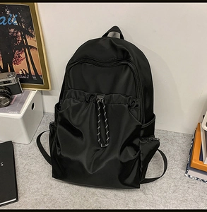 Detail of waterproof nylon backpack featuring a drawstring front pocket and side zippers