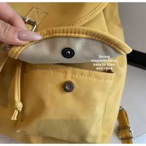 Détail d'un sac à dos jaune vif montrant la boucle magnétique et le cordon de serrage