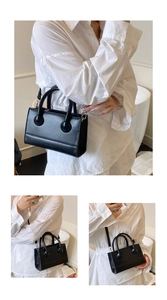 Detail of elegant black leather handbag with circular handle hardware and shoulder strap