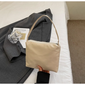 Détail du sac baguette minimaliste beige avec fermeture éclair et anneaux argentés