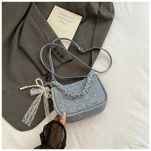 Détail du sac en jean bleu avec coutures en losange, clous métalliques et charme perle