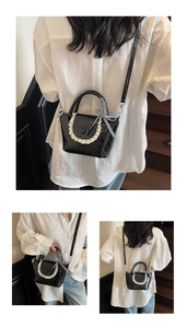 Detail of black textured crossbody bag with lace trim and checkered bow ribbon on handle