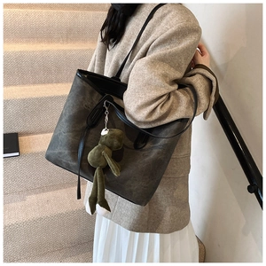 Detail of dark green oversized tote bag with plush frog pendant on interior stairs