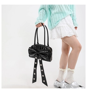 Detail of black glossy leather handbag featuring large bow with silver metallic rivets