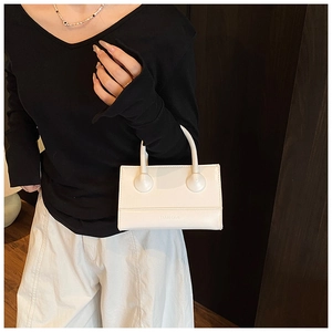 Detail of white mini box bag featuring a unique sphere design and logo on the handle