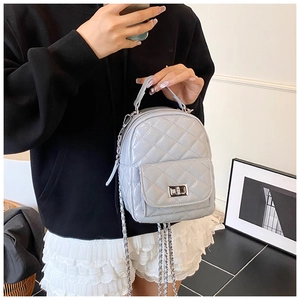 Detail eines hellgrauen gesteppten Rucksacks mit Metalldrehverschluss und Kette