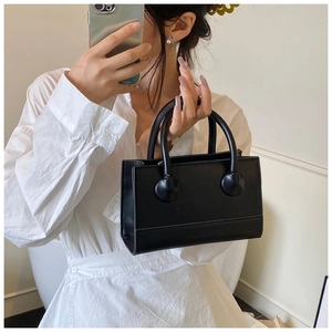 Mirror selfie showing the elegant black leather handbag with round handle buckles
