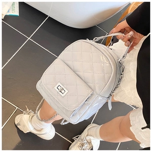 Makroaufnahme aus grauem gestepptem Lackleder mit Metalldrehverschluss und Kettendetail