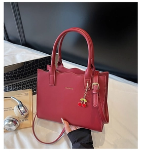 Detailansicht der roten Brauthandtasche mit Kirsch-Anhänger und stilvollen Accessoires