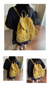 Détail d'un sac à dos en toile jaune gingembre avec deux poches avant et boucles