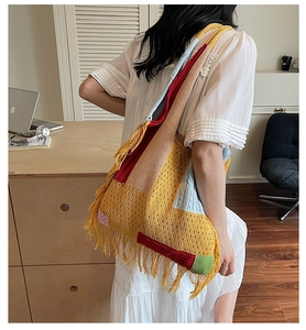Detail of bohemian knit tote bag showing colorful crochet patchwork and long fringe accents
