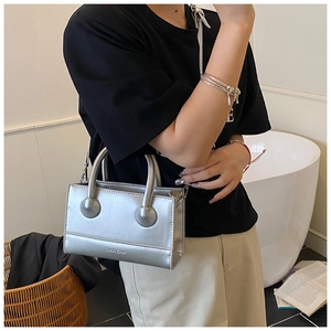 Silver metallic leather handbag detail with top handles and logo branding
