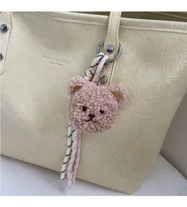Dettaglio dell'orso di peluche marrone con anello in metallo e nappa a righe sulla borsa