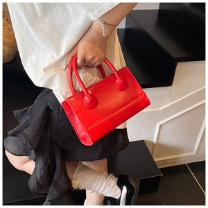 Detail view of stylish red leather handbag with round decor and embossed bag lettering
