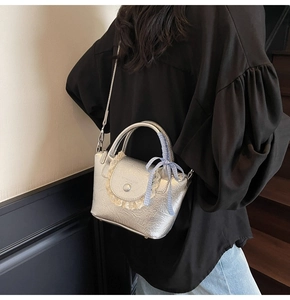 Detail of silver pleated handbag with lace trim and blue checkered bow ribbon