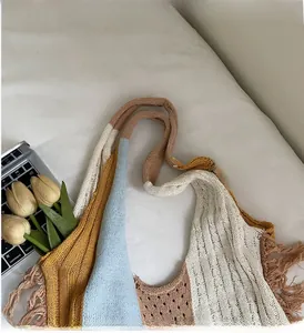 Detail shot of boho color-block knit tote bag featuring tassel fringe and cable textures