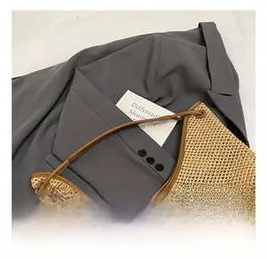 Detail showing the brown leather trim and metal eyelet on a woven straw tote bag