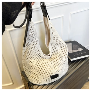 Detail of hobo bag showing cream crochet texture and black leather strap on a suitcase