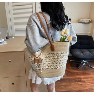 Detail of woven straw tote bag featuring hollow mesh pattern and brown leather straps