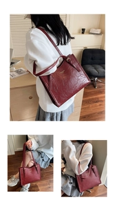 Close-up of vintage burgundy pleated leather tote bag with gold lettering detail