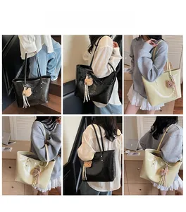 Dettaglio della borsa tote lucida nera e beige con ciondolo a forma di orso e nappa