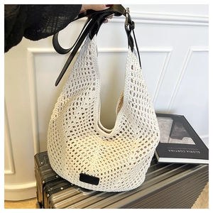 Detail of cream woven tote bag featuring large hollow crochet texture and black leather strap