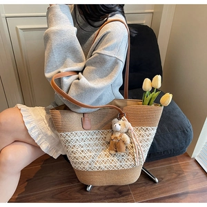 Detailed shot of straw woven tote with white lace splicing and cute bear charm