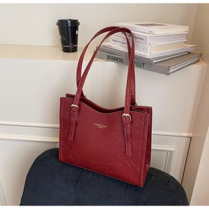 Detail of burgundy leather tote bag with vintage texture and gold brand logo lettering