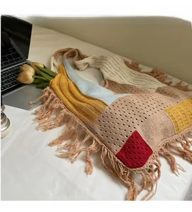 Detail of bohemian knit tote bag with colorful patchwork, fringe tassels, and hollow texture