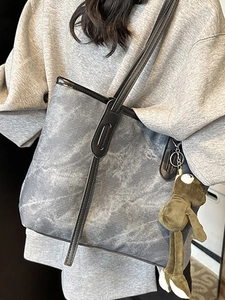 Minimalist grey marble tote bag with black straps and green frog pendant on a model