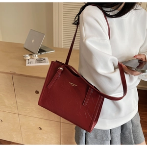 Detail of vintage burgundy tote bag with crackle leather texture and adjustable strap