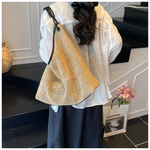 Detailed back view of a woven straw tote bag with black leather straps on a model