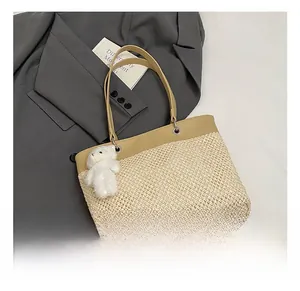 Detail show of straw tote bag with brown leather trim and cute white plush bear charm