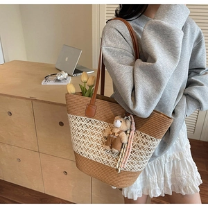 Detail of woven straw tote bag with leather strap and cute bear charm in home setting