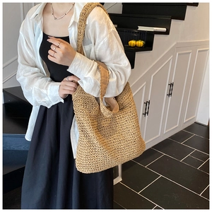 Dettaglio di una grande borsa tote in paglia beige a spalla per vacanze estive al mare