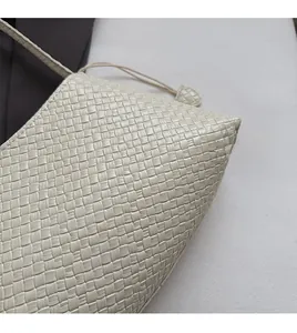 Close-up of the woven texture on a cream shoulder bag showing the premium material
