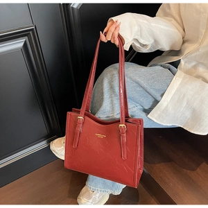 Detailed macro view of burgundy vintage leather tote bag with gold buckle straps