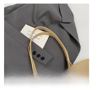 Detail showing smooth light brown handles and silver rings of the woven straw tote bag