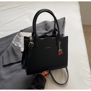 Detailansicht einer schwarzen Lederhandtasche mit Wellenrand und goldenem Markenlogo