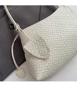 Detail of hand-woven off-white leather bag texture with slim straps and minimalist design