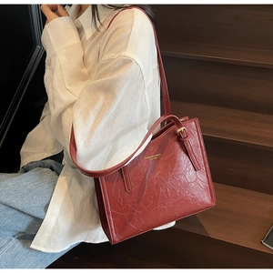 Detail of burgundy vintage tote bag featuring wrinkled leather texture and gold hardware