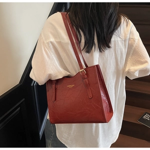 Close-up of deep red tote bag featuring gold FASHION & BAGS LEATHER logo and textured finish