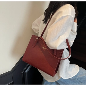Model showing the large burgundy tote bag with leather texture and gold lettering in style