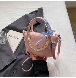 Detailed view of pink mini bag with lace trim and blue checkered bow on grey blazer