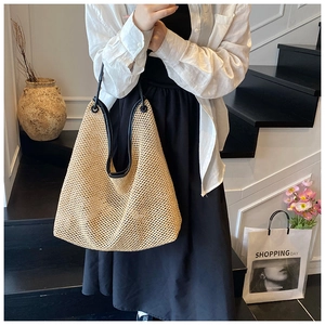 Close-up of woven straw tote bag with black leather handles and trim for beach vacations