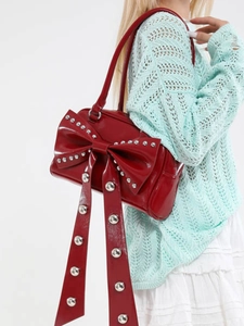 Fashionable red patent leather shoulder bag featuring a large studded bow for women