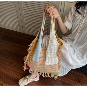 Close-up of bohemian knitted tote bag with colorful patchwork design and long fringe tassels