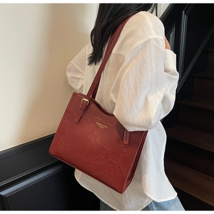 Detail of vintage red leather tote bag with gold lettering shown on shoulder